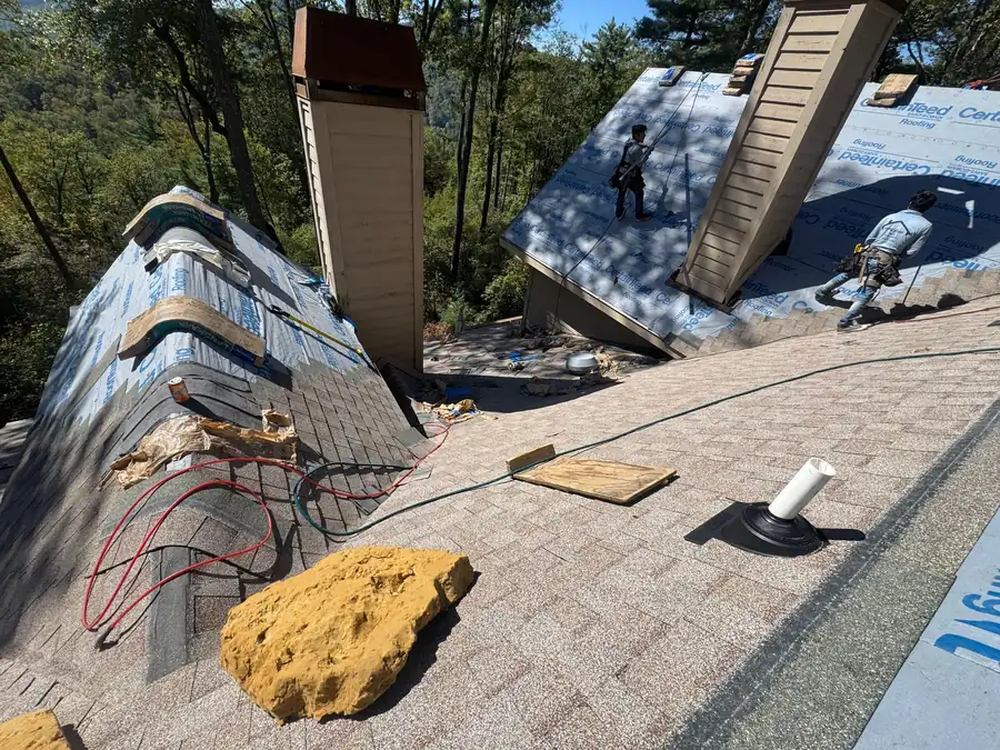Old shingles and flashing stripped back around a chimney before new material goes on